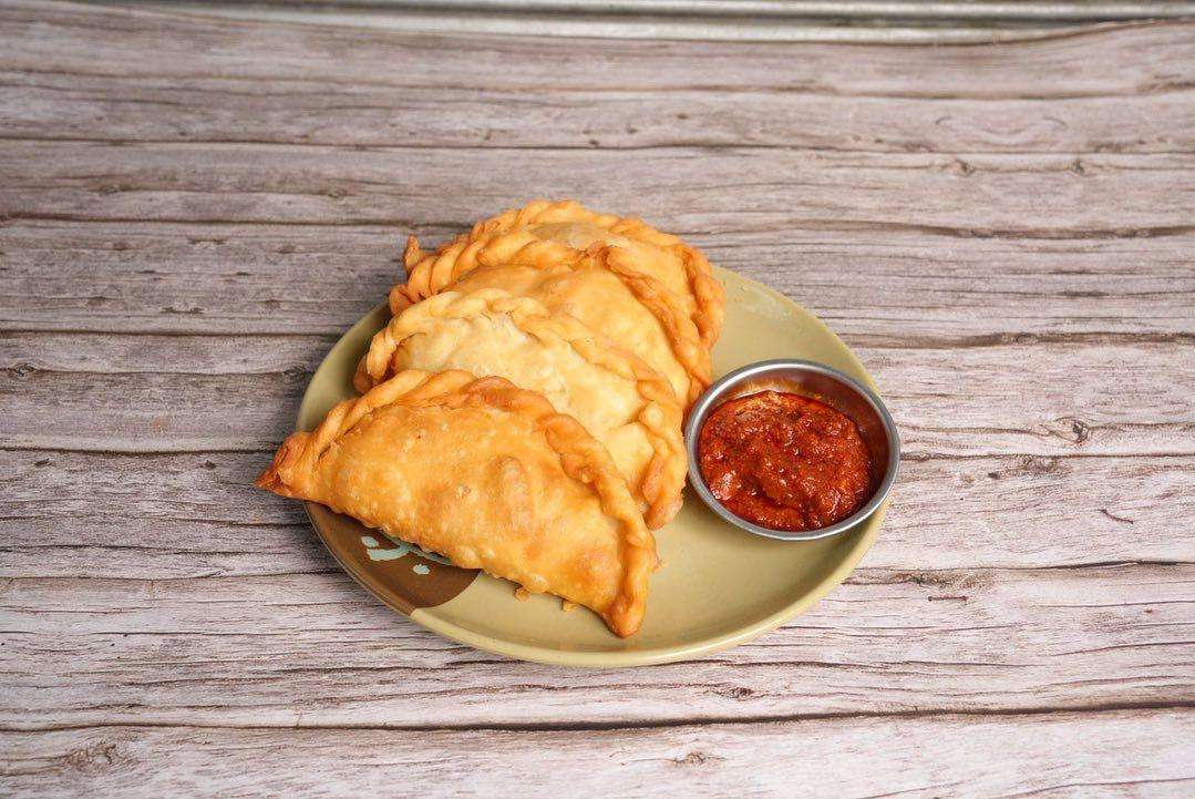 Fried Shabhale with a spicy red sauce on brown plate against a wood background.