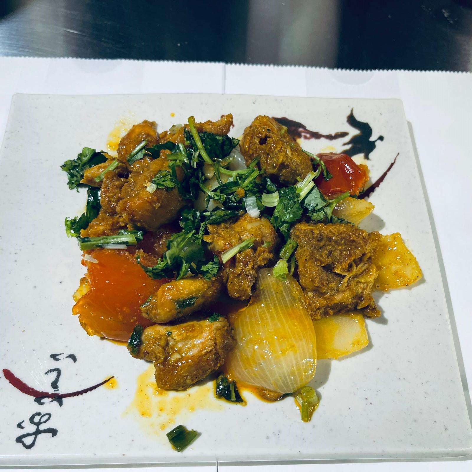Garlic Chicken served on a white plate against a dark background.