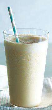 Cold Lassi drink in a tall glass white a white and teal straw against a white background.