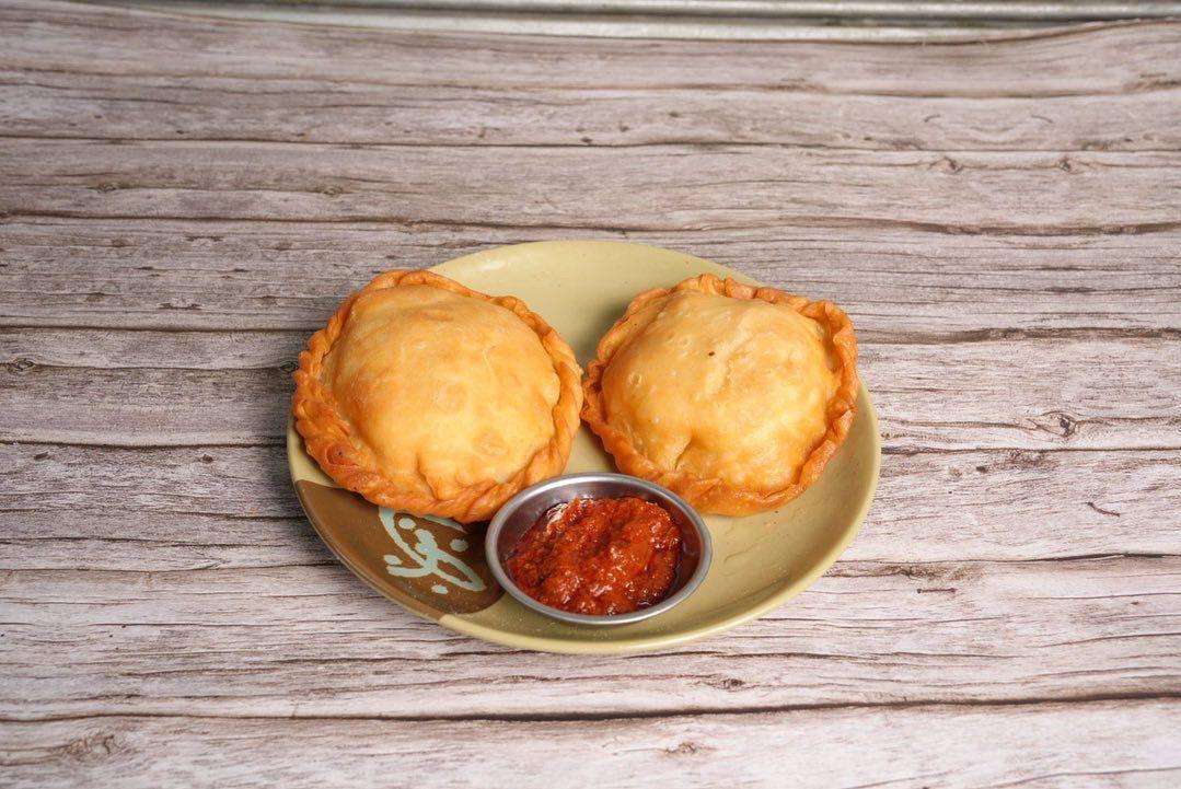 Beef Shabhale with spicy red sauce on a brown plate against a wood background.