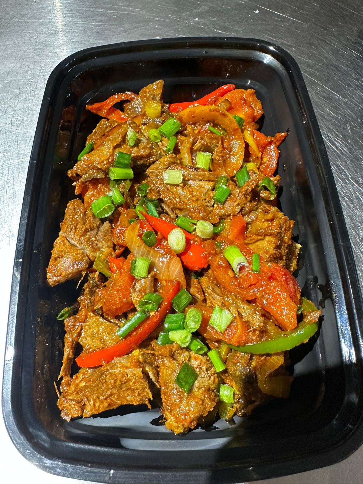 Spicy Stir Fried Beed served on a black bowl against a metal background